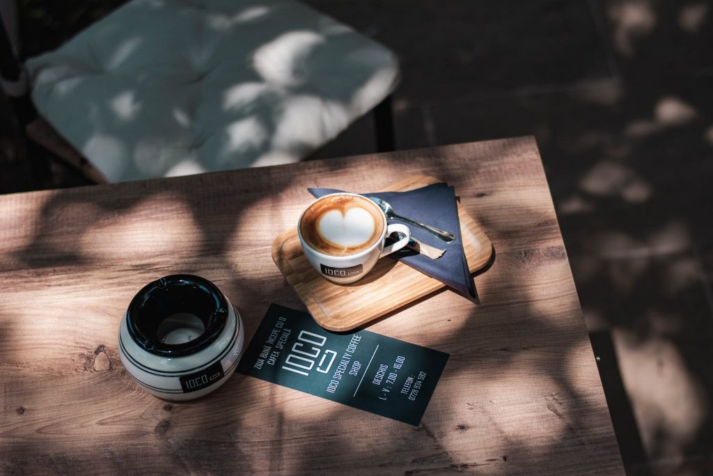 A Brochure Near a Coffee Cup on Wooden Table